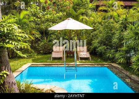 Pool with umbrella and beach beds in a tropical hotel Stock Photo