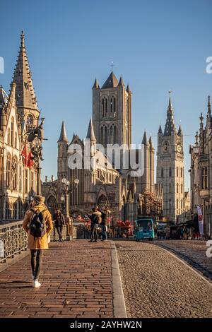 Tourists cross Saint Michael's Bridge with a view of Saint Nicholas Church in Ghent Stock Photo