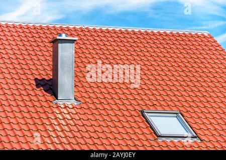 Chimney and window on clean roof of residential house. Steel home chimney close-up in summer. Modern air vent system on rooftop. Metal chimney pipe on Stock Photo