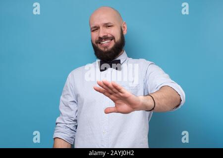 Handsome bearded man making stop sign refusing to drink alcohol on party. Studio shot Stock Photo
