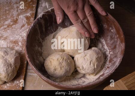 Balls of dough. Plywood cutting board, wooden flour sieve and wooden rolling pin - tools for making dough Stock Photo