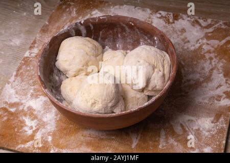 Balls of dough. Plywood cutting board, wooden flour sieve and wooden rolling pin - tools for making dough Stock Photo