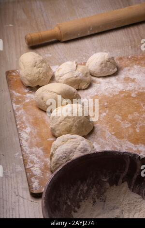 Balls of dough. Plywood cutting board, wooden flour sieve and wooden rolling pin - tools for making dough Stock Photo