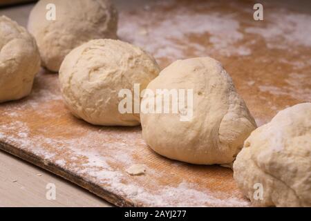 Balls of dough. Plywood cutting board, wooden flour sieve and wooden rolling pin - tools for making dough Stock Photo