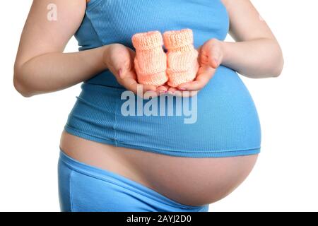 Pregnant woman holding a beautiful woolen baby shoes isolated on white Stock Photo