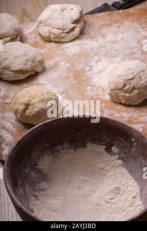 Balls of dough. Plywood cutting board, wooden flour sieve and wooden rolling pin - tools for making dough Stock Photo