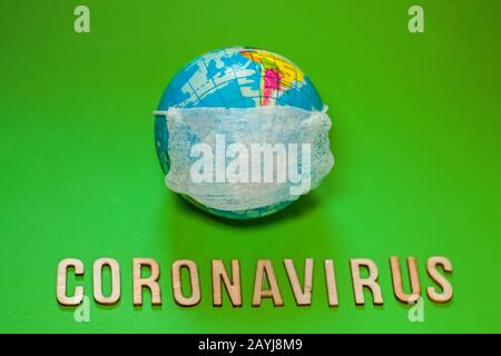 Earth planet in protective medical mask fight with text Corona virus on green background. world Corona virus attack concept. 2019 nCoV virus infection Stock Photo