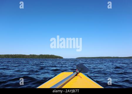 Rafting adventure first person view from yellow boat with paddle on finish lake bright sunny day blue water windy Stock Photo