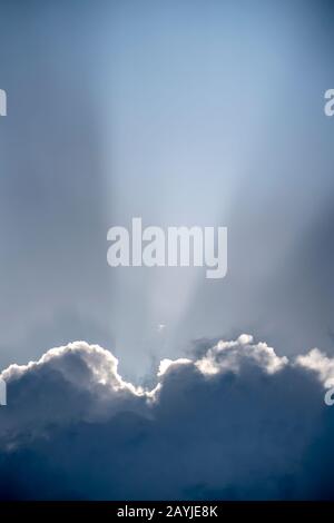 Solar beam is like a spotlight shining from behind the huge Cumulus clouds. Stock Photo