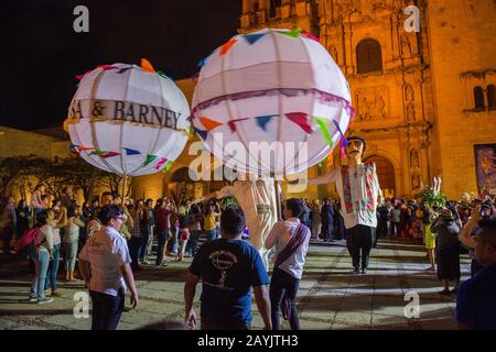 Women dressed in a regional costume and giant puppets dressed as a bride and groom during a Calenda, a procession on the Plaza Santo Domingo, celebrat Stock Photo