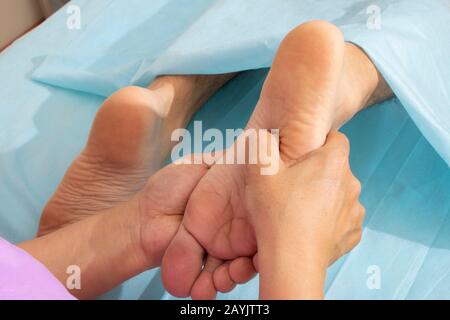 Health care worker giving orthopedic massage to man feet, horizontal Stock Photo