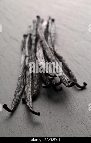 Bundle of dried bourbon vanilla beans or pods on black stone board with selective focus Stock Photo