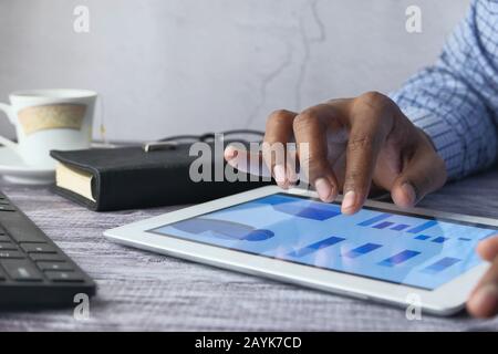 Close up of man hand analyzing chart on digital tablet  Stock Photo