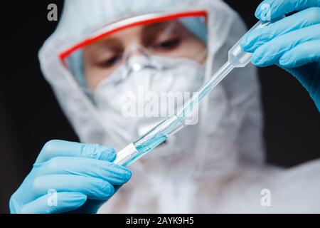 Medic in white hazmat protective research scientist work blood test in modern laboratory. Blue color, corona virus epidemic Stock Photo
