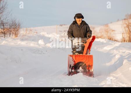 Man cleaning snow from sidewalks with snowblower machine winter Stock Photo