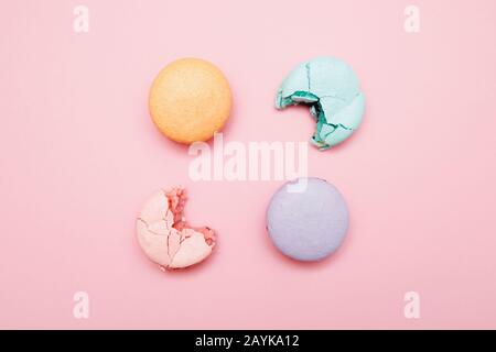 Minimalism, bitten macaroons on pink background, top view. Concept reducing interest rates on loans in banks, taxes Stock Photo