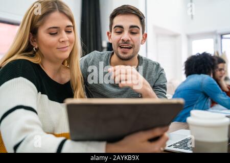 Two creative designers working in a project together, reading something on digital tablet and sharing new ideas on workplace. Business and team work c Stock Photo