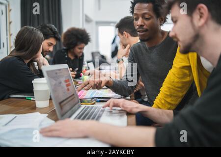 Creative designers working in a project together and sharing new ideas on workplace. Business and team work concept. Stock Photo