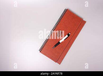 Closed notebook in leather binding with pen on a gray background. Place for text. Stock Photo