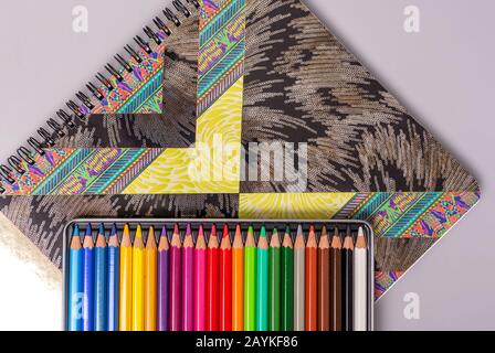 A box with sharpened multi-colored pencils lies on a sketchbook. Items for creativity. Stock Photo
