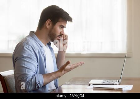 Frustrated man talk on cell having laptop problems Stock Photo