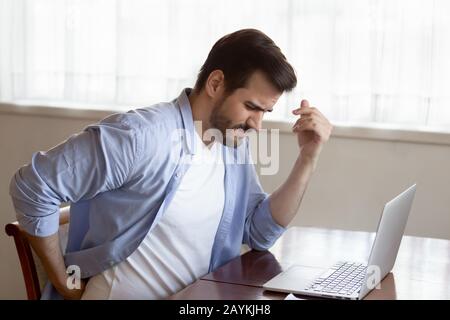 Unwell young man suffer from working in incorrect posture Stock Photo