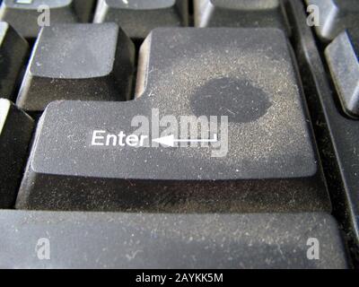 Close up of very dirty black keyboard key with an inscription Enter. Button covered with a layer of dust with a fingerprint. Unhygienic equipment in h Stock Photo