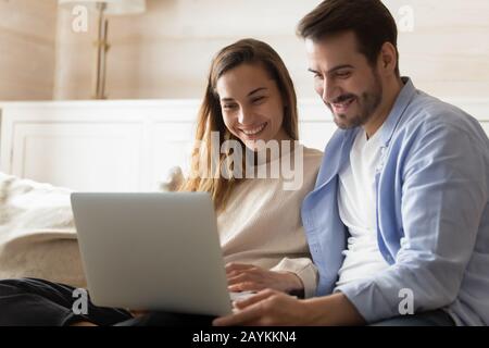 Happy young couple relax at home using laptop Stock Photo