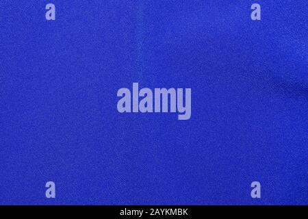 The texture of a knitted woolen fabric textile in classic blue trendy color. Abstract background for design with soft waves. Stock Photo