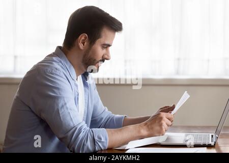 Focused millennial man read letter at home Stock Photo