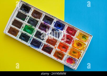 Working artist tools, mixing paints, creative, top view. Accessories to drawing on yellow and blue color background. Stock Photo