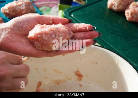 A girl with a beautiful black manicure makes homemade cutlets from minced meat. Stock Photo