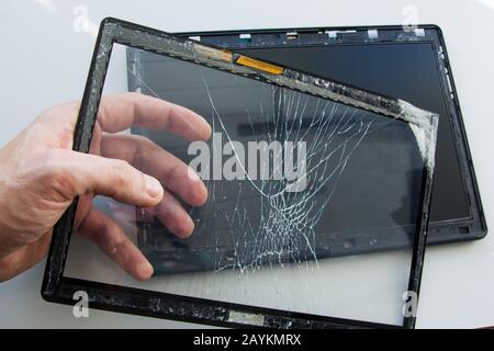 Cracked tablet computer with broken glass touch screen. A technician is fixing and replacing the broken screen on damaged gadget. Repair device in ser Stock Photo