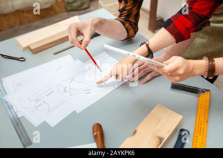 Man and woman workers engineers discussing the project drawing in the workshop Studio Stock Photo