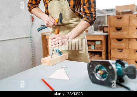 Man carpenter working with a hammer and chisel, close-up on his hands Stock Photo