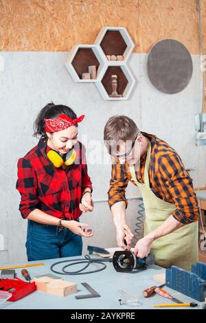 Man and woman carpenters working together in a wood workshop. Cooperation and blue collar concept Stock Photo