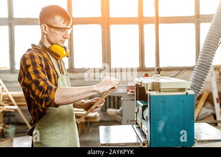 Professional carpenter man working on a machine with a wooden workpiece. Hobby and industry concept Stock Photo