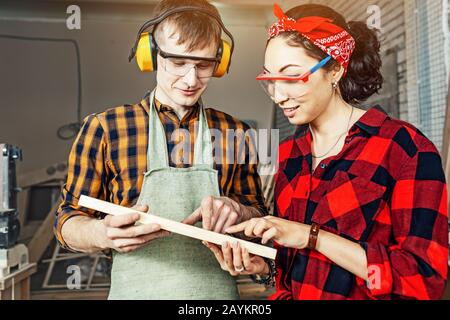 Man and woman working with wood in workshop of factory Stock Photo