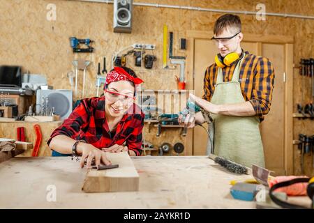 man and woman as a team working in the workshop with wood and polishing it with mechanical tools Stock Photo