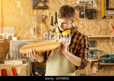 Man carpenter holding a finished product made of wood - cutting Board for the kitchen Stock Photo