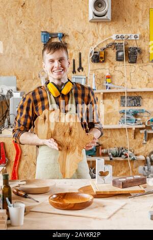 man craftsman carpenter holds in his hands piece of wood in the shape of a Africa map Stock Photo