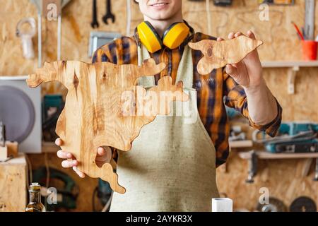man craftsman carpenter holds in his hands piece of wood in the shape of a North America map Stock Photo