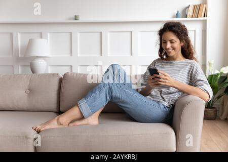 Smiling pretty young woman using funny mobile apps. Stock Photo