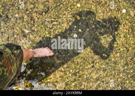 Shallow selfie of a persons shadow standing in a creek Stock Photo