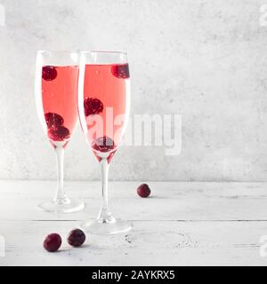 Kir Royal Champagne Cocktail on white, copy space. Flute glasses with berry sparkling champagne drink for celebrating or chilling. Stock Photo