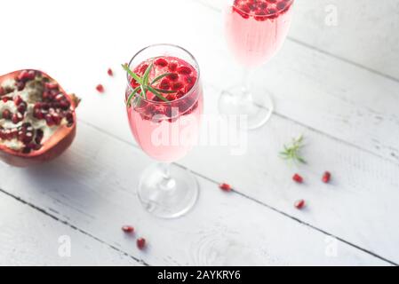 Mimosa cocktail with Rose Champagne, Pomegranate and Rosemary in flute glasses,  close up. Mocktail, Mimosa sparkling pink drink. Stock Photo