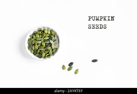 Pumpkin Seeds in bowl. Unshelled pumpkin seeds, healthy raw food ingredient, isolated on white background, top view, copy space. Stock Photo
