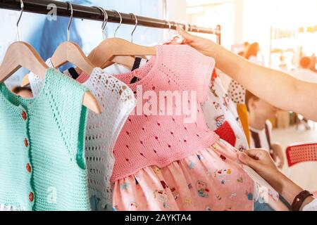 Happy woman Mother shopping at the clothes store, choosing dress for her litlle daughter Stock Photo