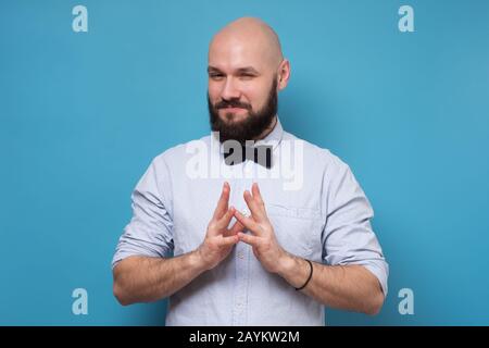 Cunning tricky mature man thinking lookingat camera with hand together over blue background. Concept of unfair game Stock Photo