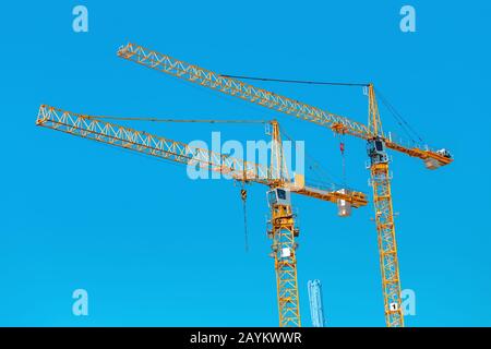 Two construction cranes against blue sky Stock Photo